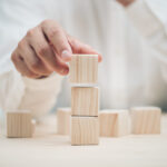 Hand arranging three wood cube stacking. Business concept growth success,hand stack woods block step on table. business development concept.copy space.